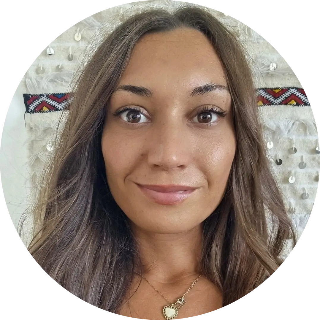 Oceane Sabeur, experte de voyage Portrait en gros plan avec fond décoratif blanc orné de motifs colorés et de petits éléments brillants.