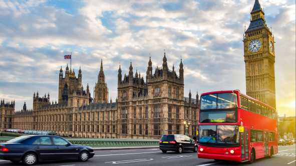 Houses of Parliament mit Big Ben und Doppeldeckerbus auf der Westminster Bridge bei Sonnenuntergang, London, UK