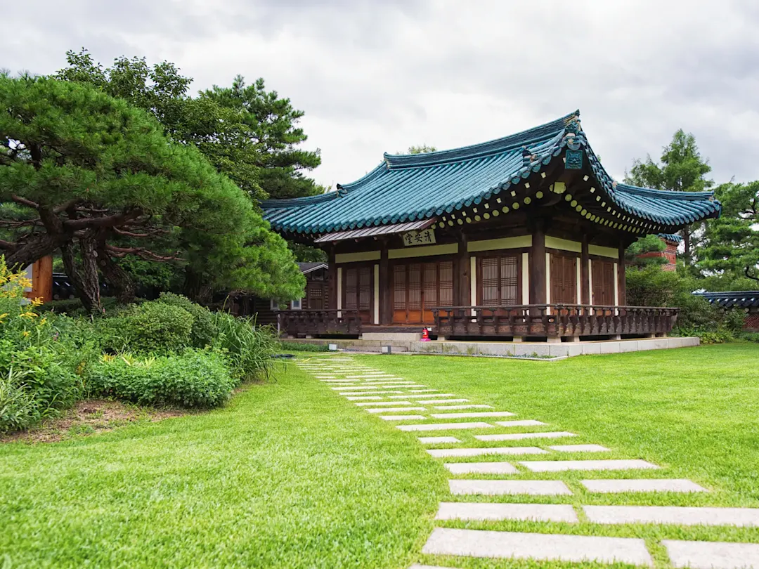 Traditionelles koreanisches Haus mit blauem Ziegeldach inmitten eines gepflegten Gartens. Südkorea.