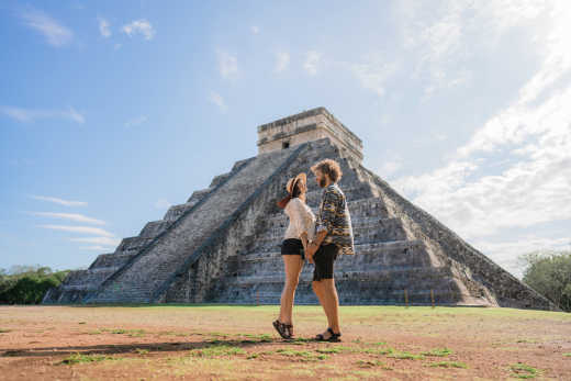 Junges kaukasisches heterosexuelles Paar vor dem Hintergrund der Chichen Itza-Pyramide in Mexiko

