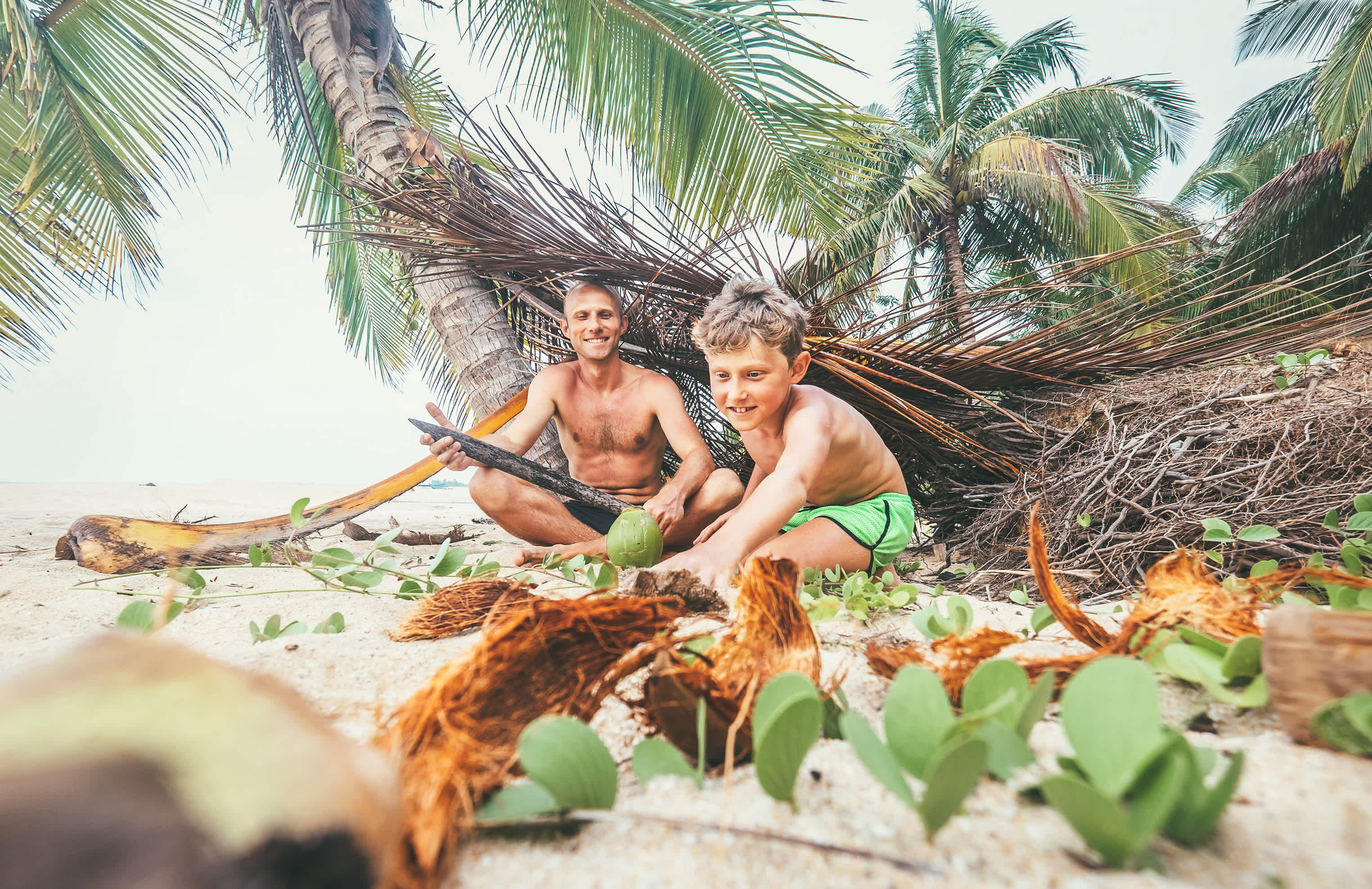 Vater und Sohn baute eine Hnütte aus Ästen auf einem tropischen Strand. 
