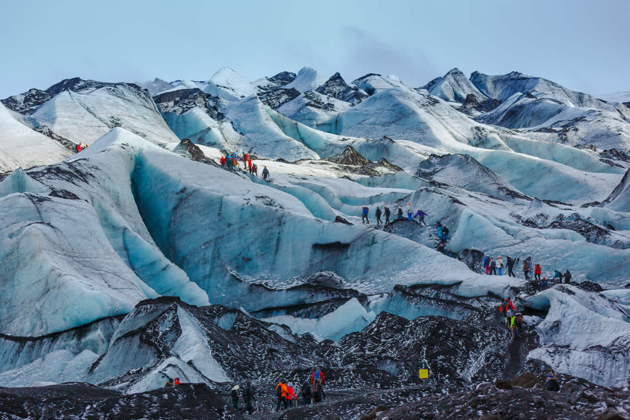 Des groupes de personnes font une randonnée sur le glacier de Solheimajokull