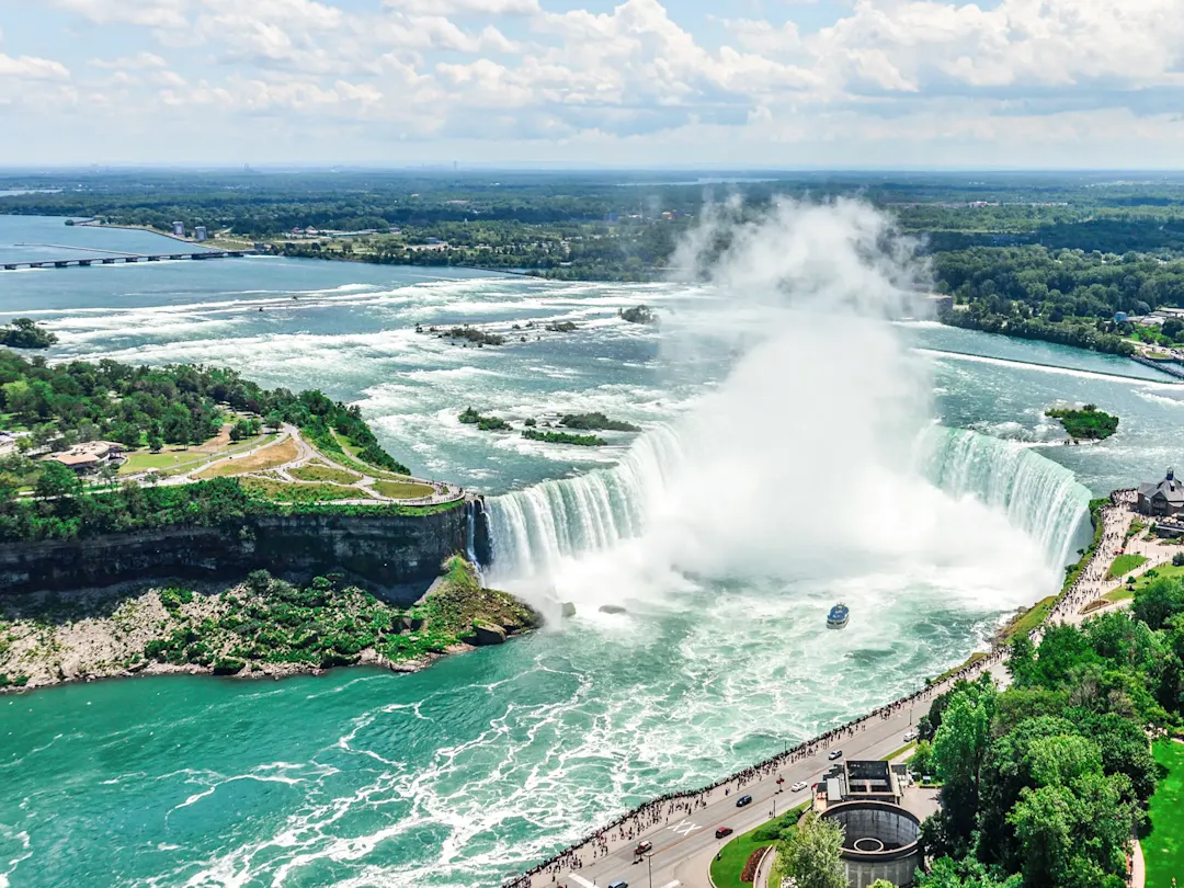Majestätische Niagarafälle mit Boot und grüner Landschaft. Niagara Falls, Ontario, Kanada.