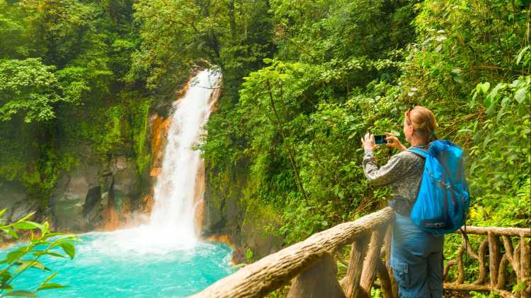 Une femme près de la chute d'eau turquoise au Costa Rica
