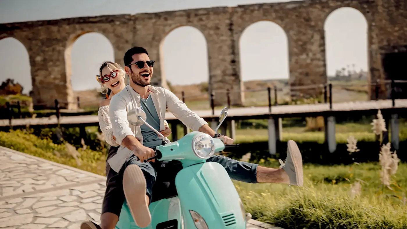 Glückliches junges paar Reiten Retro-Scooter in mediterranen Altstadt

