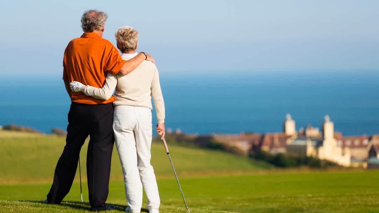 Golferin und Golfer von hinten, die sich umarmen und auf einem Golfplatz stehen