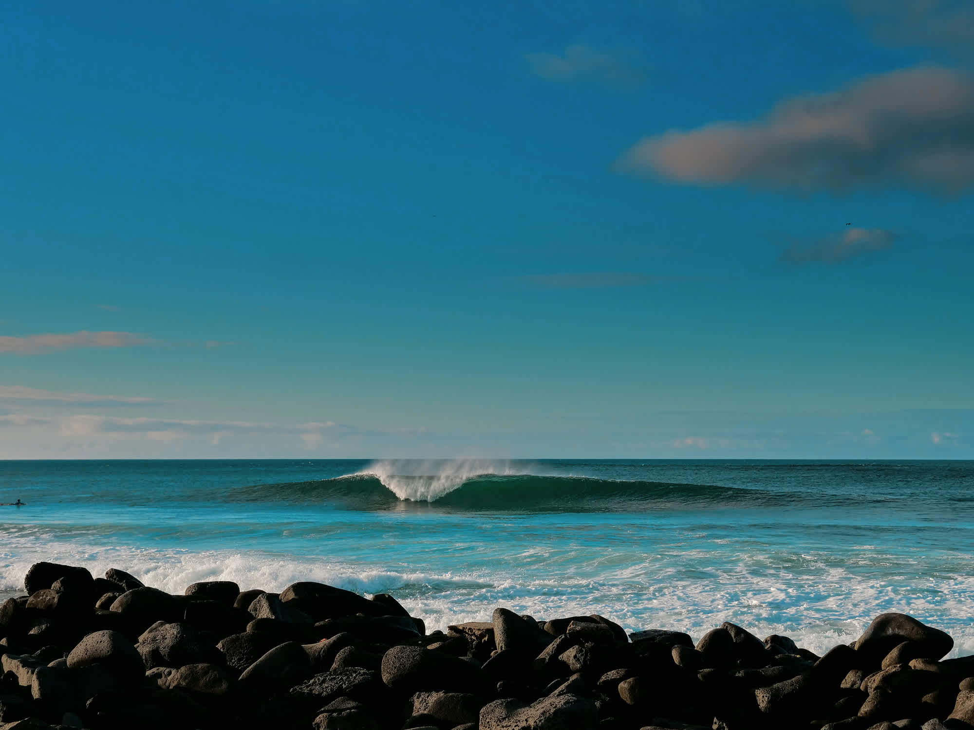 A high wave on the ocean by the rocky seashore. 