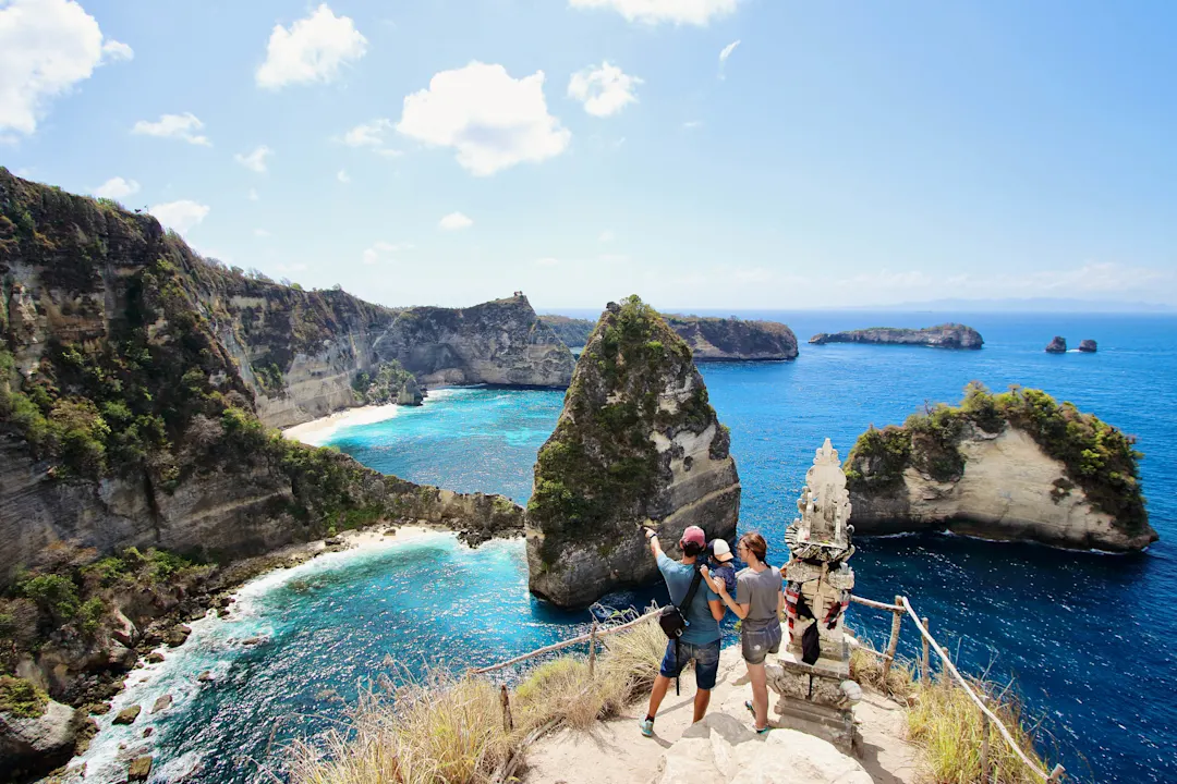 Junge Eltern und kleines Kind genießen die Aussicht in Thousand Islands Viewpoint, auf den schönsten Plätzen in Nusa Penida Island, Indonesien, Bali