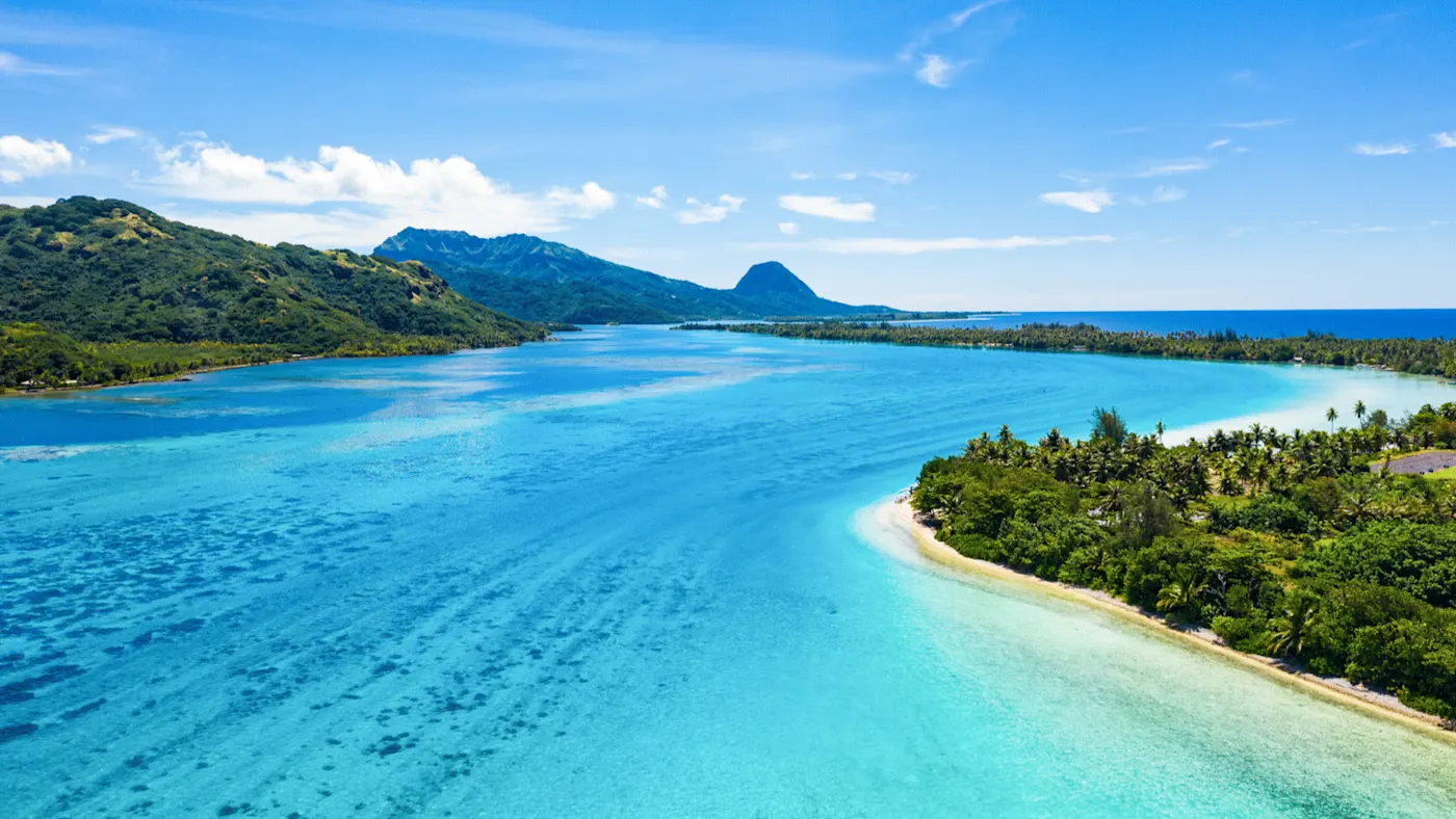 Huahine, Französisch-Polynesien Luftbild einer Lagune mit türkisblauem Wasser, umgeben von grünen Hügeln und Palmen. Huahine, Französisch-Polynesien.