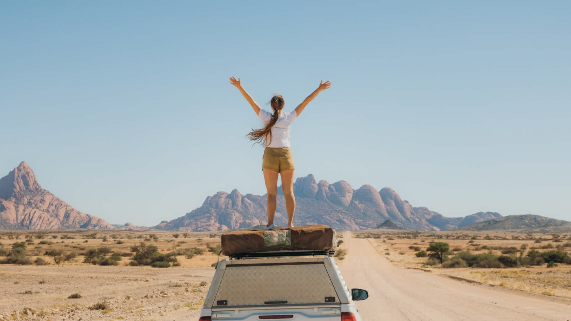 Femme sur le toît d'un 4x4 lors d'un roadtrip en Namibie