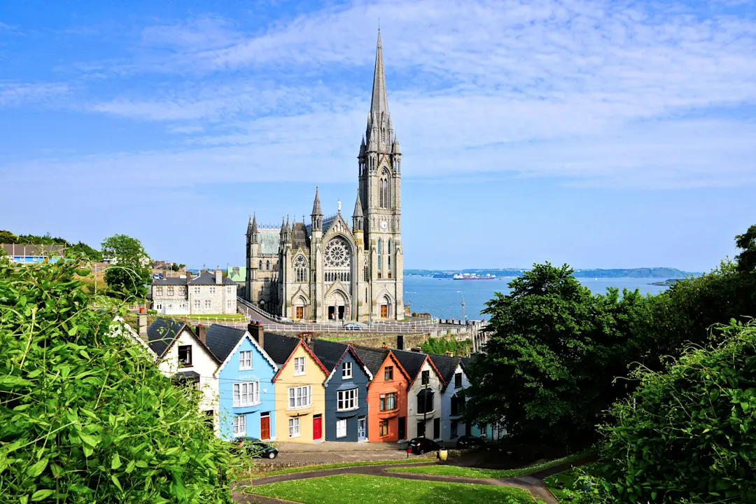 Irland, Cork, Kathedrale Bunte Reihenhäuser mit hoch aufragender Kathedrale im Hintergrund in der Hafenstadt Cobh, County Cork, Irland