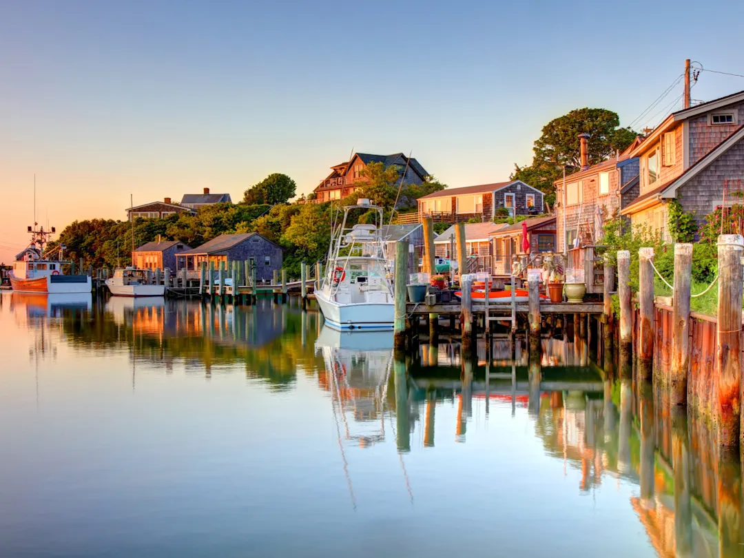 Idyllischer Fischerhafen mit Booten, Holzhäusern und ruhigem Wasser im Abendlicht, Cape Cod, Neuengland, USA. 