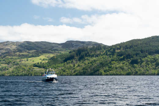 Bateau sur le lac entouré d'un paysage verdoyant, Loch Ness, en Écosse