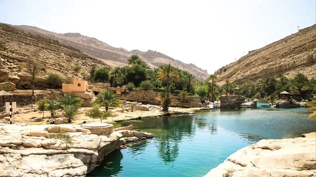 Türkisblaue Wasserpools und üppige Palmen inmitten der Felslandschaft. Ibra, Ash Sharqiyah, Oman.