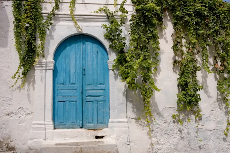 Kreta, Griechenland Alte Hausfassade mit blauer Holztür und Efeu, traditioneller Stil, Kreta, Griechenland.