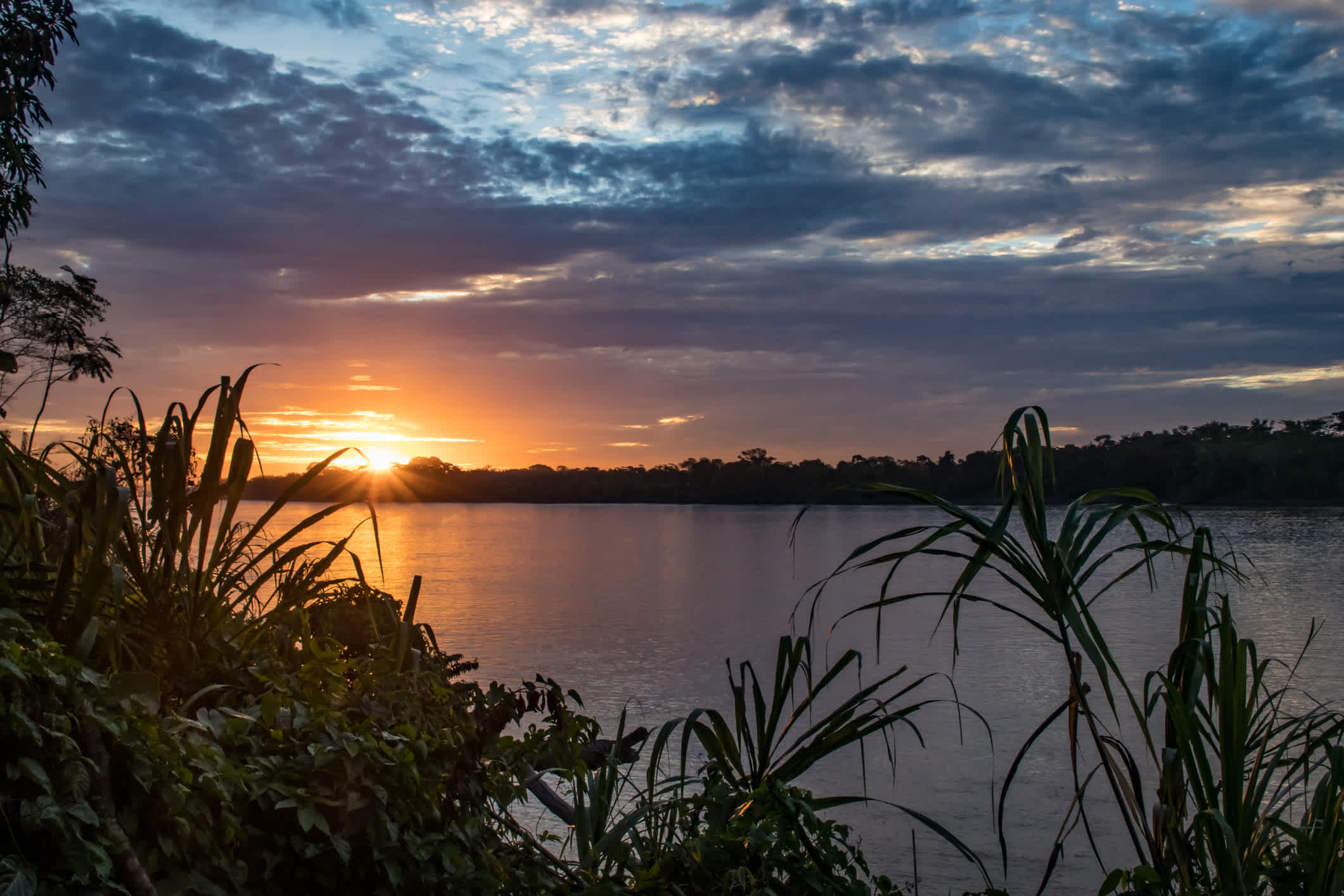Sonnenuntergang über dem Tambopata Fluss in der Amazonas-Region in der Nähe von Puerto Maldonado, Peru.