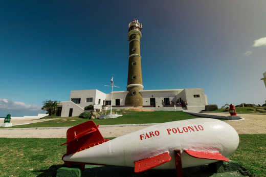 Petit avion rouge et blanc avec le phare en arrière-plan, à Cabo Polonio, en Uruguay