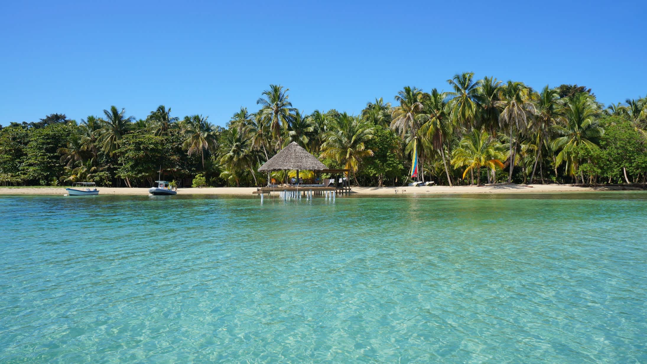 Tropische Küste mit Kokosnusspalmen und einer Palapa über dem Wasser, Bocas del Toro, Karibisches Meer, Panama