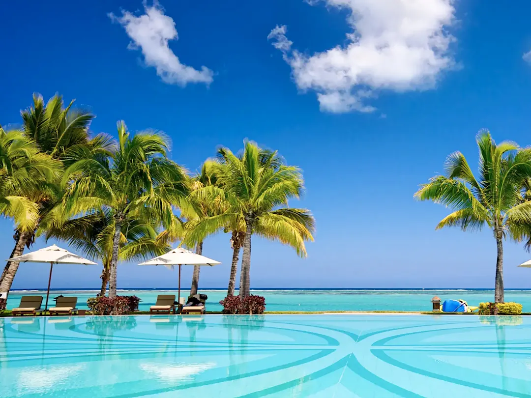 Luxuriöser Infinity-Pool mit Blick auf das Meer, umgeben von Palmen. Mauritius.