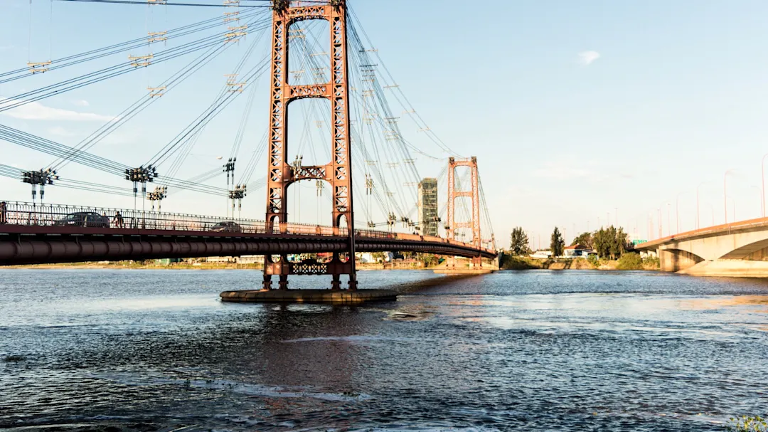 Historische Hängebrücke über einen ruhigen Fluss bei Sonnenuntergang. Santa Fe, Santa Fe, Argentinien.