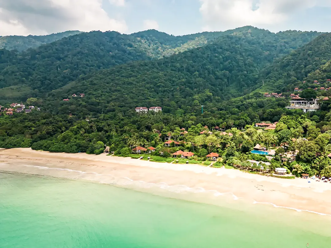 Grüner Hügel und ruhiger Sandstrand in tropischer Umgebung. Koh Chang, Thailand.