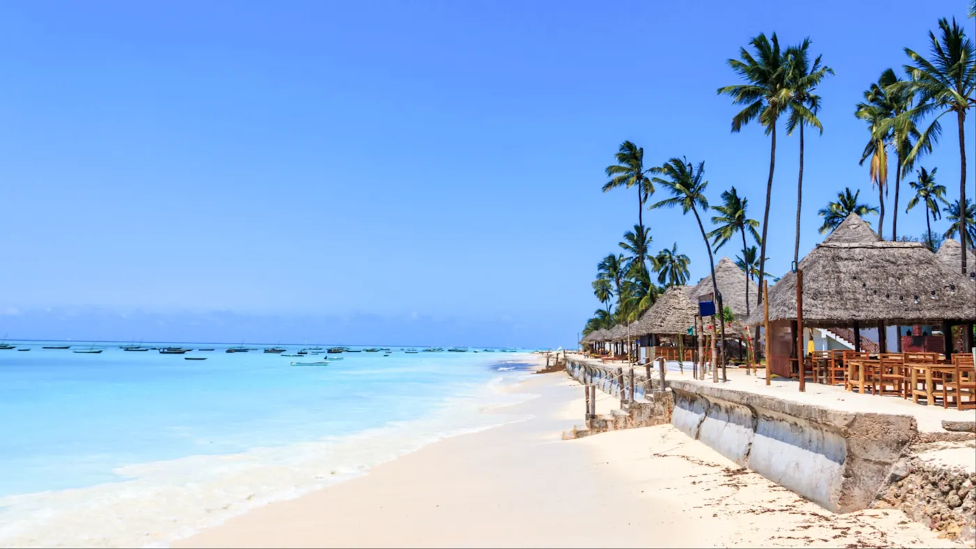 Nungwi, Sansibar, Tansania Weißer Sandstrand mit Palmen und Strohhütten am türkisblauen Meer. Nungwi, Sansibar, Tansania.
