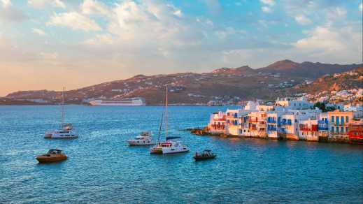 Hafen von Mykonos beim Sonnenuntergang mit Kreuzfahrtschiff und Yachten, Griechenland.