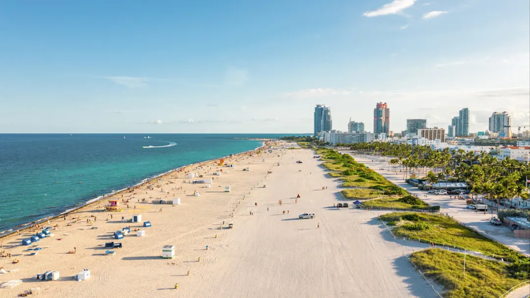 Luftaufnahme eines weiten Sandstrands mit Stadt im Hintergrund. Miami, Florida, USA.