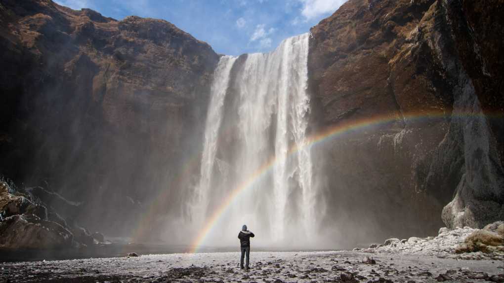 Europe, Iceland, Skógafoss Waterfall cascades from a cliff with a rainbow.