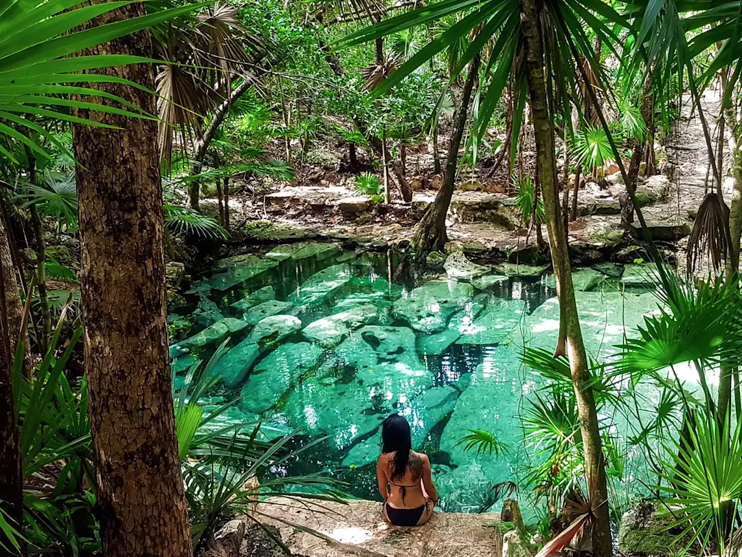 Frau sitzt an einem türkisblauen Cenote. Tulum, Quintana Roo, Mexiko.
