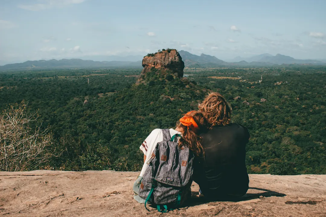 Paar genießt Aussicht auf den Sigiriya-Felsen in Sri Lanka, umgeben von grünem Dschungel unter blauem Himmel.