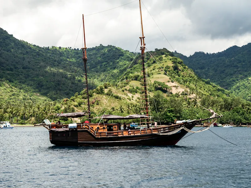 Indonesien, Lombok Ein Boot auf dem Wasser vor grünen Hügeln, Lombok, Indonesien.