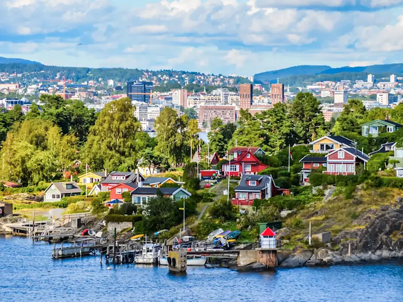 Bunte Holzhäuser am Wasser mit Blick auf die Hauptstadt. Oslo, Norwegen.