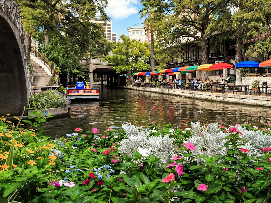 Malerische Uferpromenade mit bunten Sonnenschirmen und Booten. San Antonio, Texas, USA.
