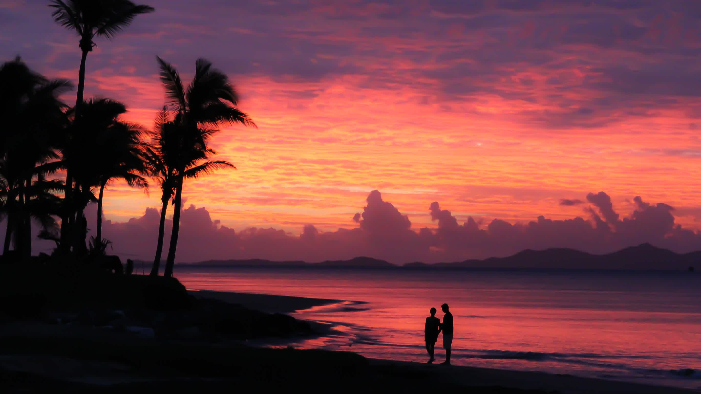 Silhouettes au bord de l'eau sur la plage au coucher du soleil, à Denarau Island, aux îles Fidji