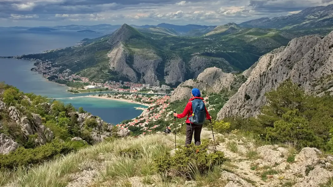 Wanderer blickt auf Küstenstadt zwischen Bergen und Meer, Omis, Dalmatien, Kroatien