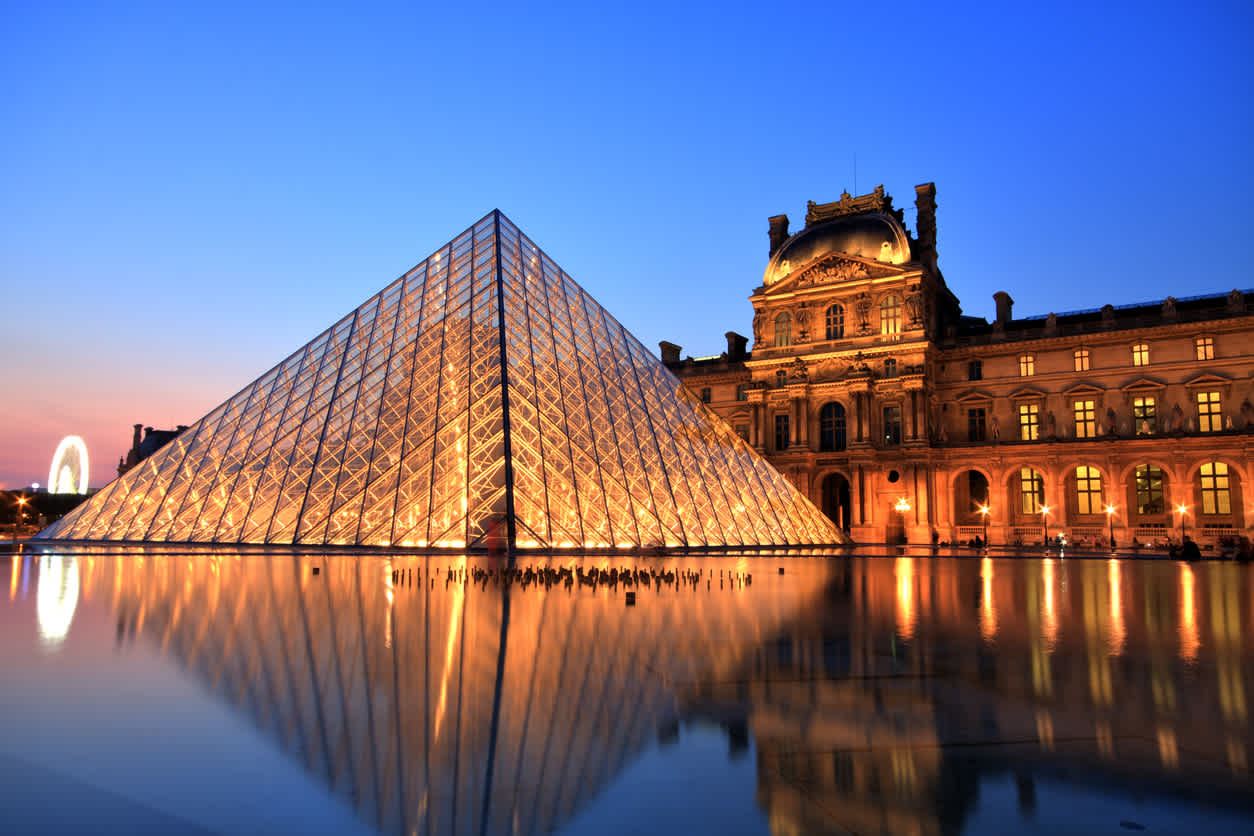 Discover amazing attractions like the Louvre, pictured here at night, as part of a Paris vacation package