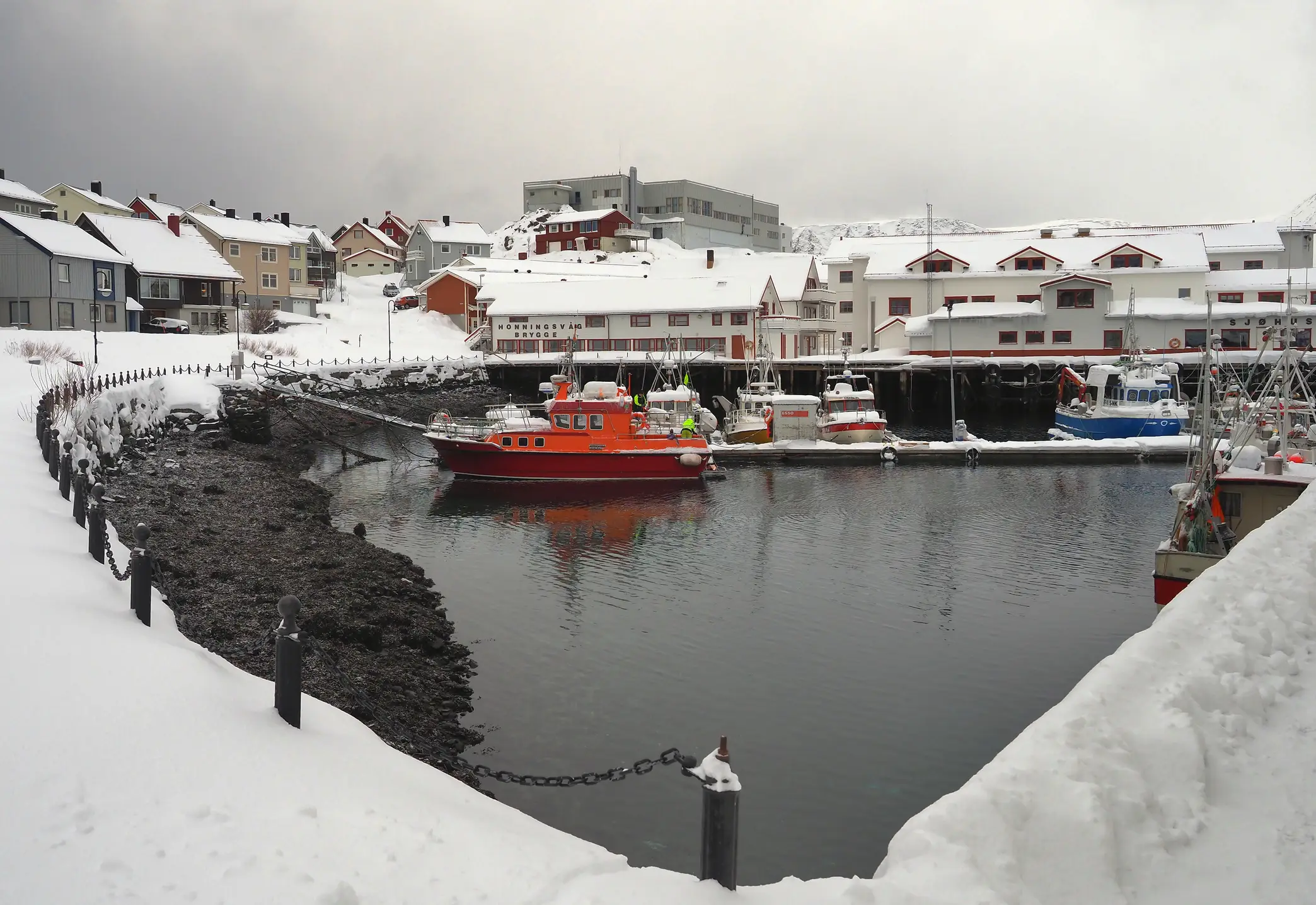 Hafen im verschneiten Fischerdorf Honningsvåg mit bunten Fischkuttern