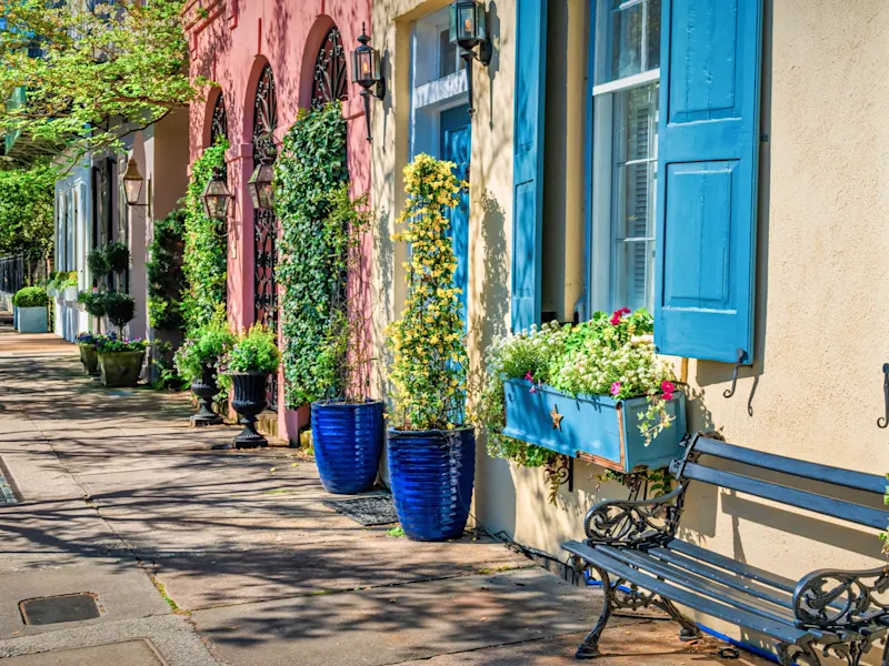 Bunte Häuser mit Blumen und dekorativen Details in einer sonnigen Straße. Charleston, South Carolina, USA.