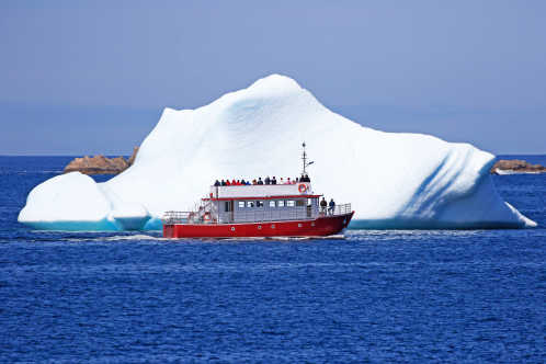 Ein Ausflugsboot fährt nahe an einem Eisberg in Twillingate, Neufundland, Kanada.