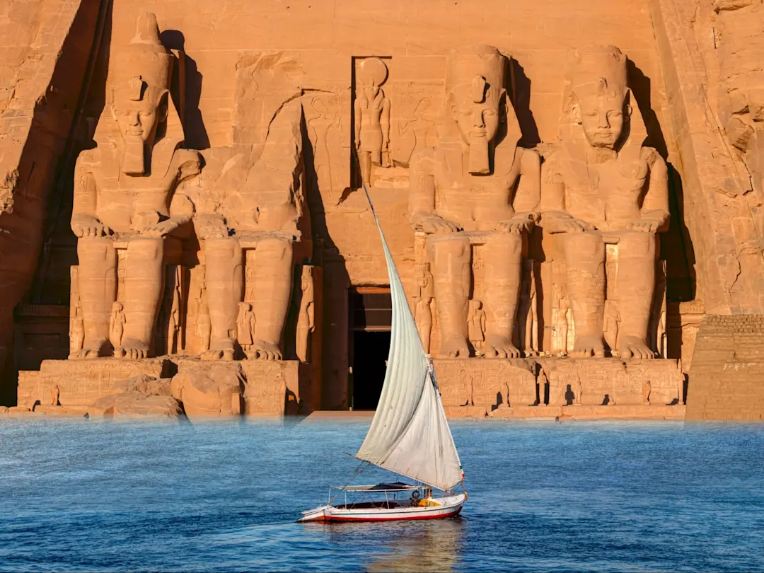 Felukenboot vor den monumentalen Ramses-Statuen des Abu-Simbel-Tempels. Abu Simbel, Aswan, Ägypten.