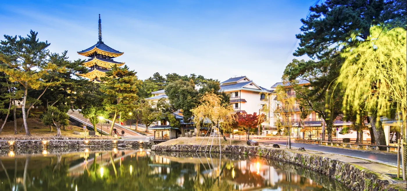 Nara, Japan Beleuchtete Pagode mit Spiegelung im Teich, umgeben von Bäumen. Nara, Japan.