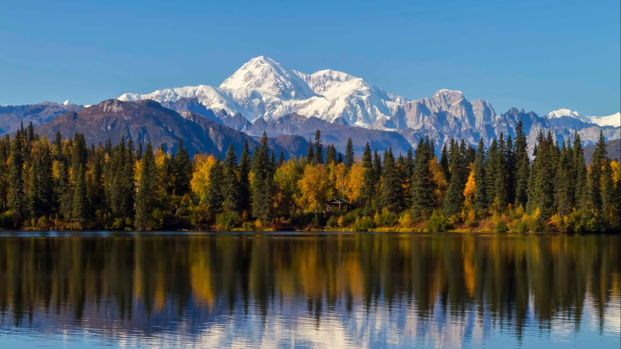 Grand lac devant forêt et montagne enneigée au Parc national de Denali, en Alaska