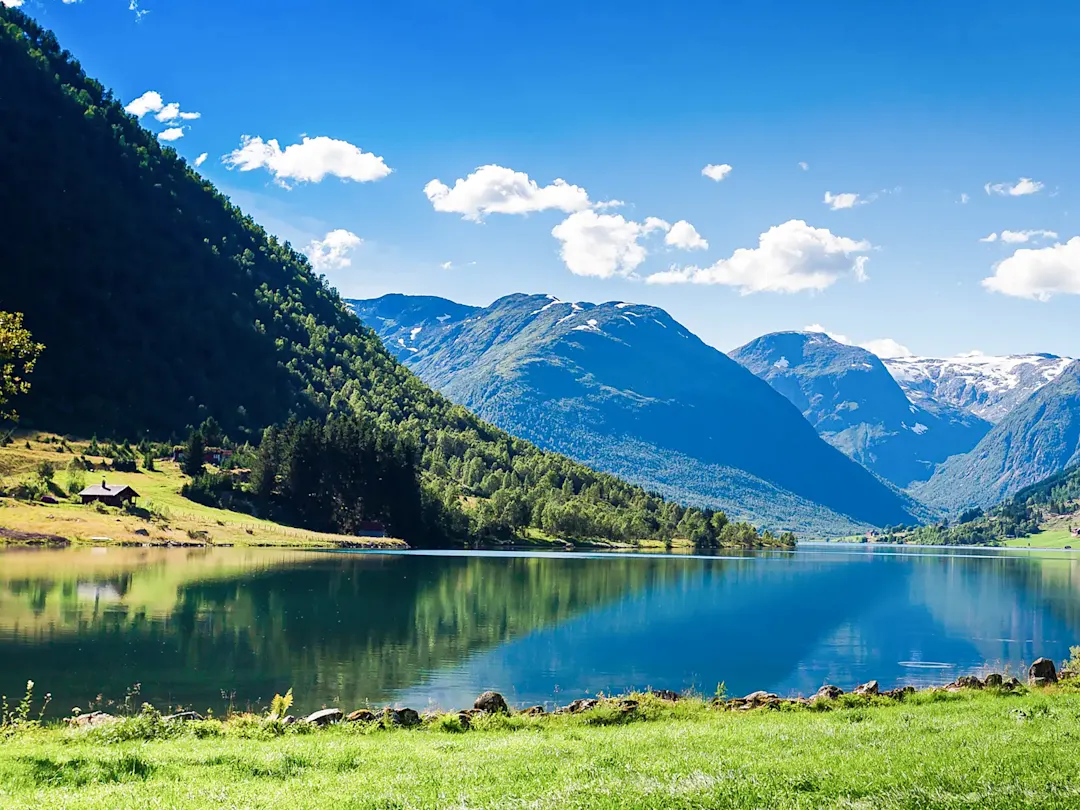 Malerischer See mit grünen Bergen und klarem Spiegelbild. Lovatnet, Vestland, Norwegen.