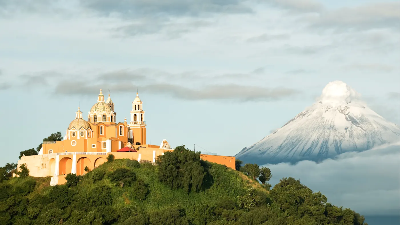 Puebla, Puebla, Mexiko Die Kirche Nuestra Señora de los Remedios auf einem Hügel mit dem Vulkan Popocatépetl im Hintergrund. Puebla, Puebla, Mexiko.