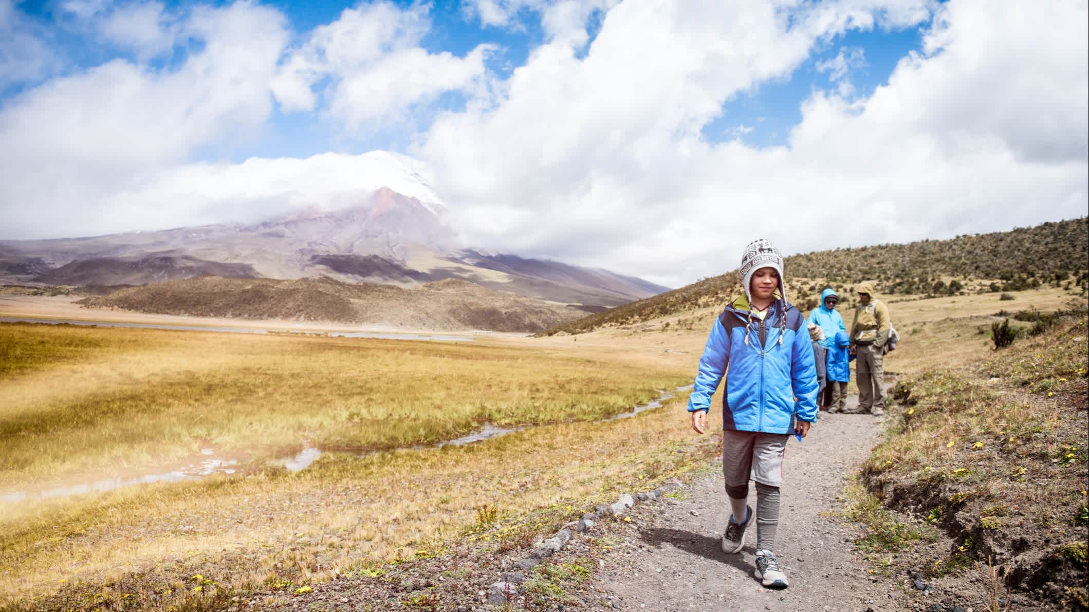 Famille marchant sur un sentier avec le volcan Cotopaxi en arrière-plan, en Équateur.