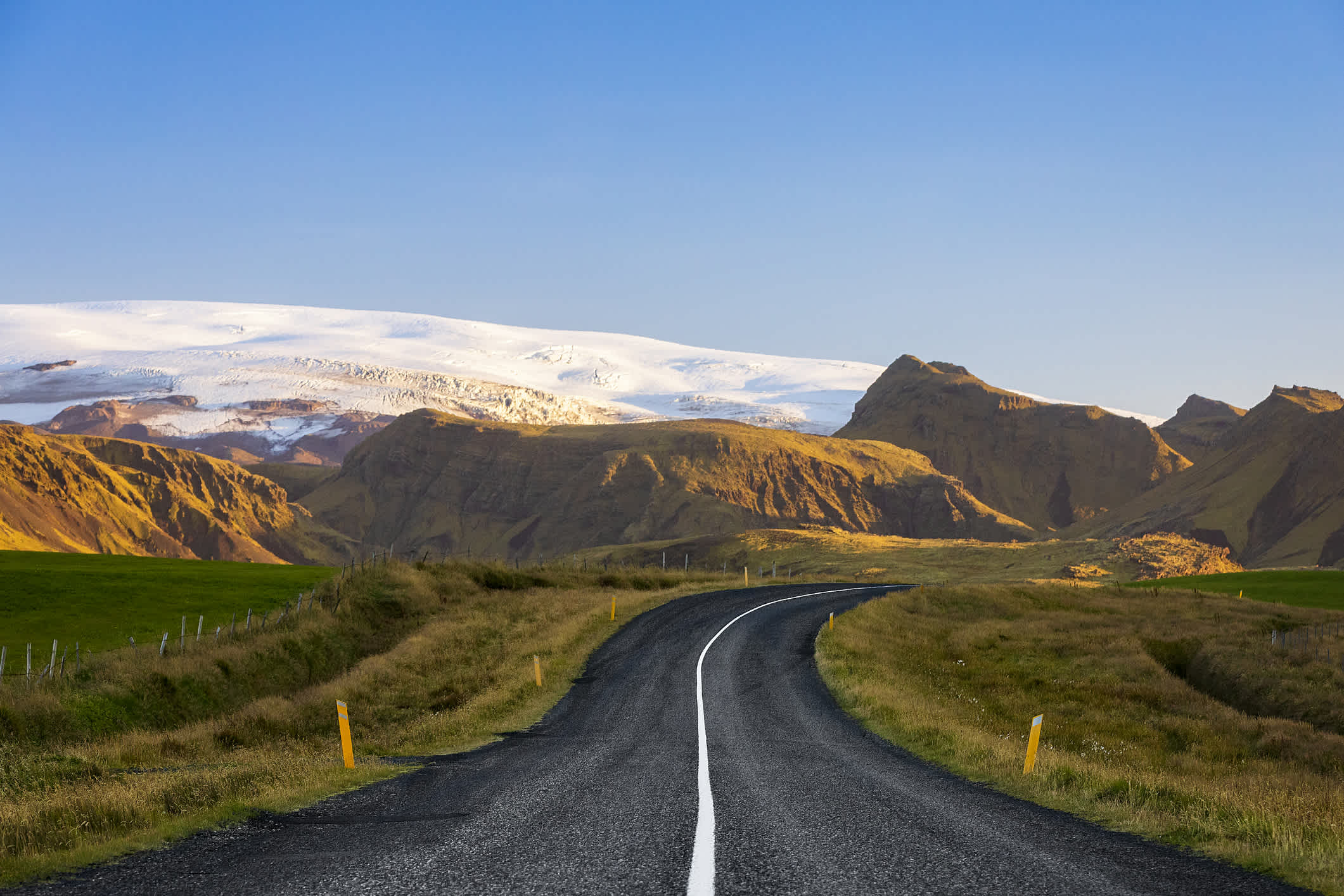 Breite Straßen entlang durch die faszinierende Natur des Golden Circle in Island, im Hintergrund weiße schneebedeckte Berge