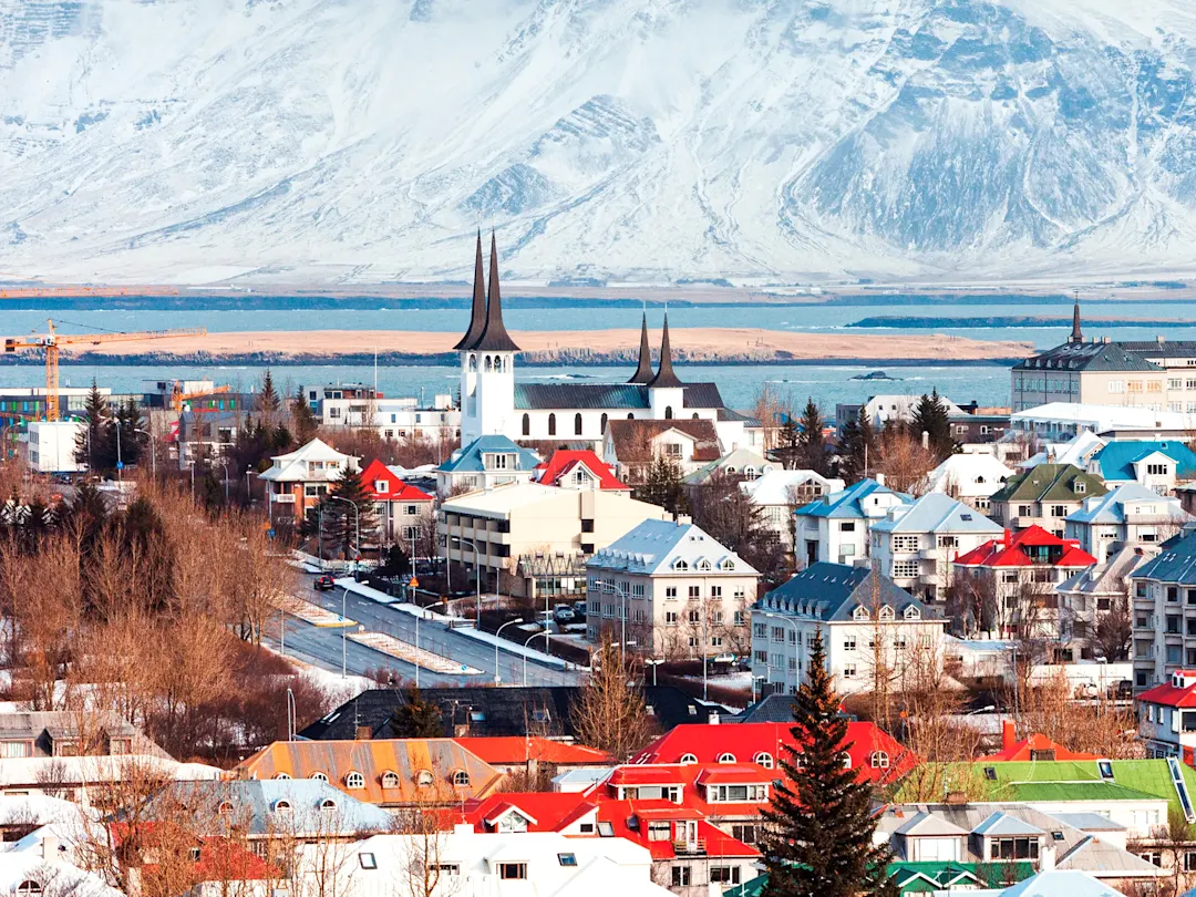 Island, Reykjavík Winterliche Stadtlandschaft mit bunten Häusern und verschneiten Bergen. Reykjavík, Island.