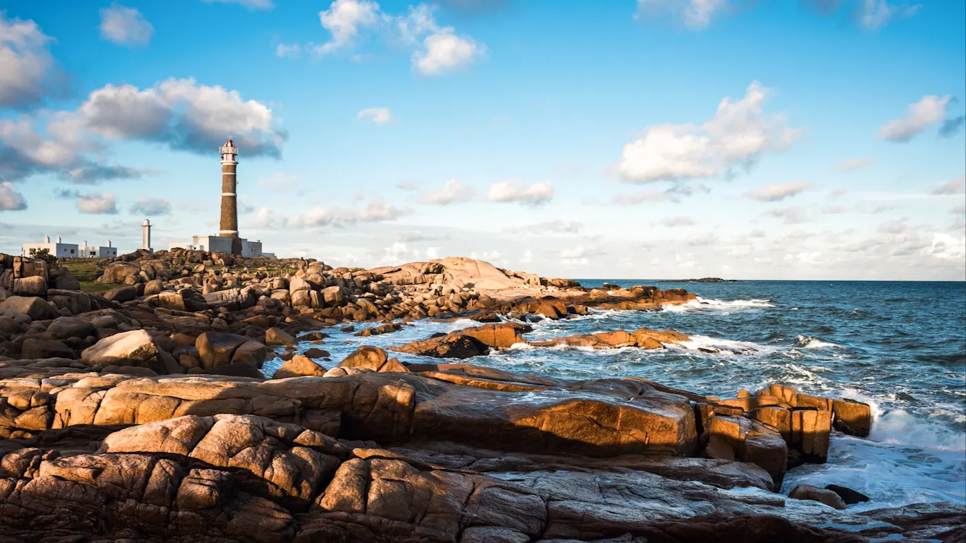 Cabo Polonio, Rocha, Uruguay Felsige Küste mit einem Leuchtturm im Hintergrund und blauem Himmel. Cabo Polonio, Rocha, Uruguay.