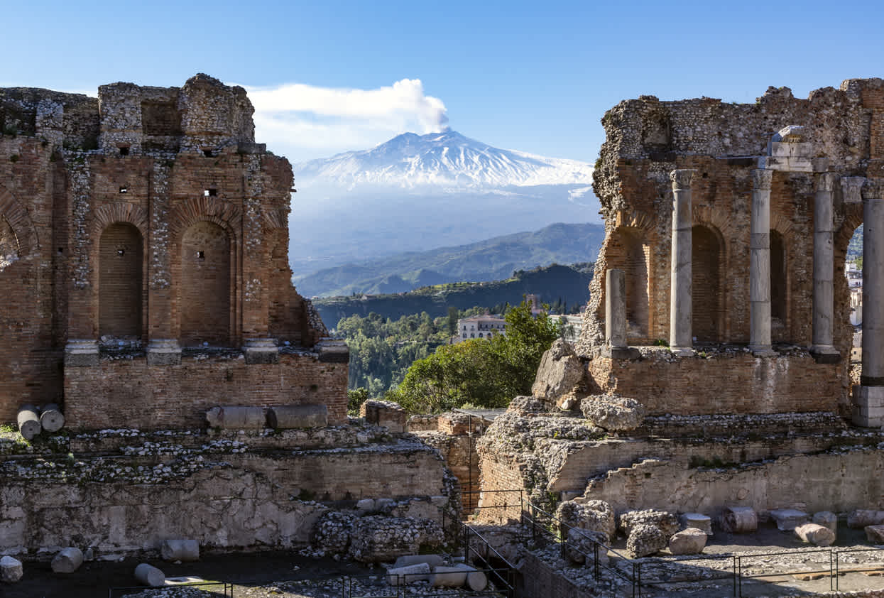 Le volcan Etna en Sicile vu à travers les ruines de l'amphithéâtre antique de Taormina.